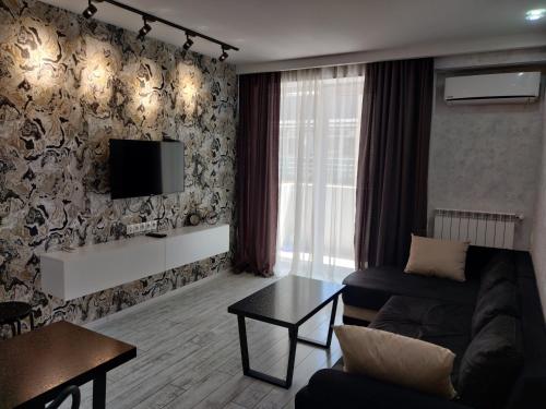 sala de estar con sofá y TV en la pared en Tbilisi App 1 en Tiflis
