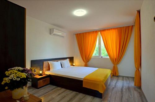 クラネヴォにあるDi Mare Holiday Apartmentsのベッドルーム1室(オレンジ色のカーテンが付いた大型ベッド1台付)