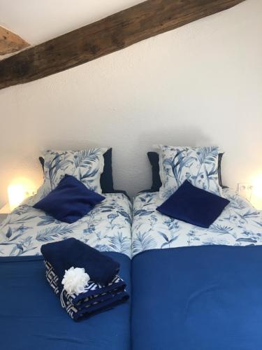 a bed with blue sheets and blue pillows at Gites Còr Causy MIMOSA in Causses-et-Veyran