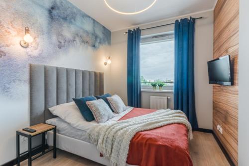Schlafzimmer mit einem Bett mit blauen Vorhängen und einem Fenster in der Unterkunft Sapphire Premium Apartment in Graudenz