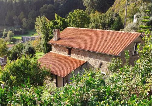 ein Haus mit einem orangefarbenen Ziegeldach in der Unterkunft Casa da Oliveira in Cariño
