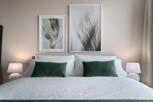 a bedroom with a white bed with two pictures on the wall at SHS HOMES-LUXE HIGHRISE, 2 BEDROOMS, KITCHEN, FREE PARKING, STUNNING VIEW, LARGE TARRASSE, Workspace in Hasselt