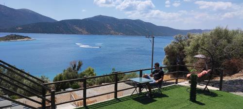 two people sitting on a balcony overlooking a body of water at Paraiso Azul Villas in Áyios Dhimítrios