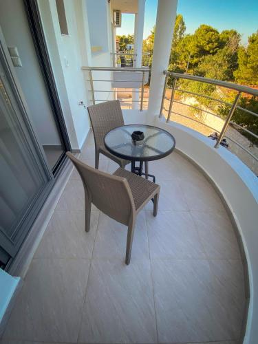 a balcony with a table and two chairs on it at Sun Day Apartments Free Airport Shuttle in Artemida
