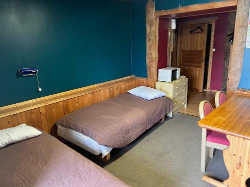 a bedroom with two beds and a table and a desk at Hotel Repvåg in Repvåg