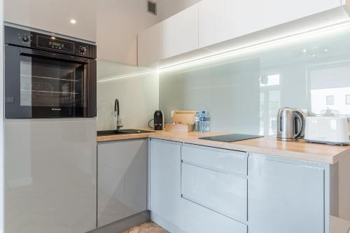 uma cozinha com armários brancos e um aparelho preto em Copper Apartment em Grudziądz