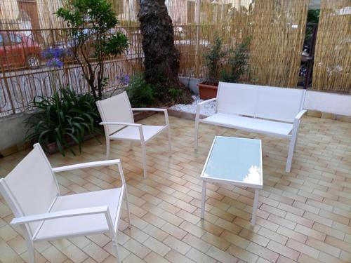 un grupo de sillas y mesas blancas en un patio en La casa di Anna, en Patti