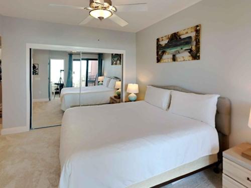 1 dormitorio con 1 cama blanca grande y espejo en Palm Beach Club 249, en Pensacola Beach