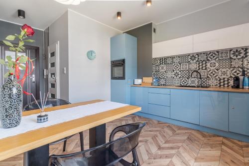 a kitchen with blue cabinets and a table with chairs at Lead Apartment in Grudziądz