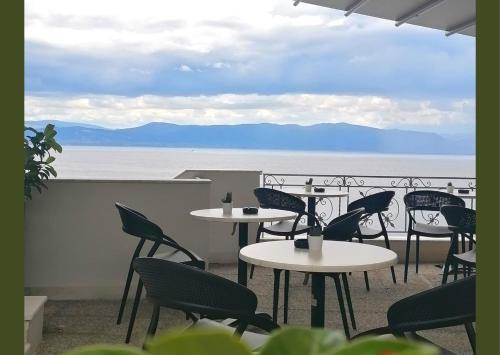 a patio with tables and chairs and a view of the ocean at Anemolia Studios in Loutra Edipsou