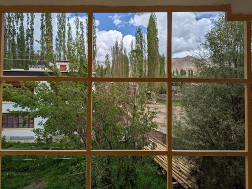 a window with a view of a field and trees at Chandan Guest House in Leh
