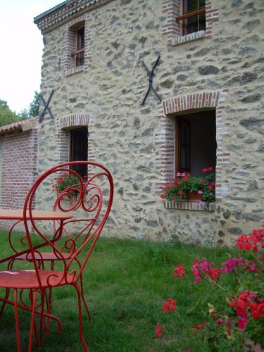 a red bench sitting in front of a stone building at Le Moulin de Drapras in Chemillé