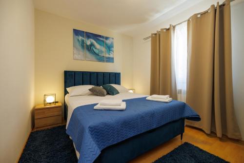 a bedroom with a blue bed with two towels on it at Apartman La vista e' bella in Kornić