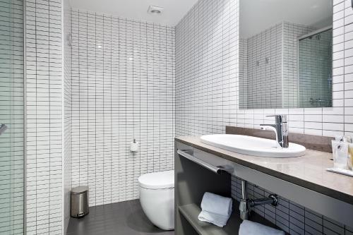 a white bathroom with a toilet and a sink at Hotel Acta Laumon in Barcelona