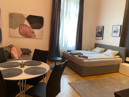 ein Wohnzimmer mit einem Bett, einem Tisch und Stühlen in der Unterkunft Stylish Apartment by the Vígszínház Theater in Budapest