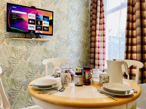 樸次茅斯的住宿－Clive Crest house，一张桌子,上面有盘子和餐具,还有一台电视