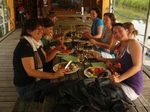 un grupo de personas sentadas alrededor de una mesa comiendo comida en De Boot, en Merkem