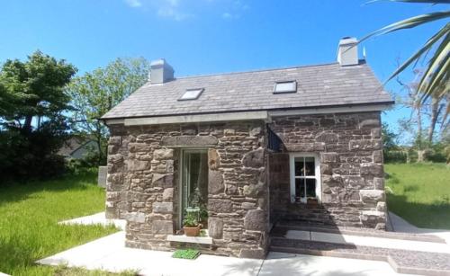 una pequeña casa de piedra sentada en un patio en Dingle Woodland Cottage, en Dingle