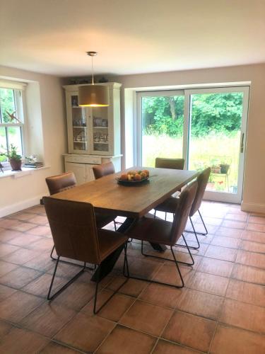 Dingle Woodland Cottage في دينغل: غرفة طعام مع طاولة وكراسي خشبية