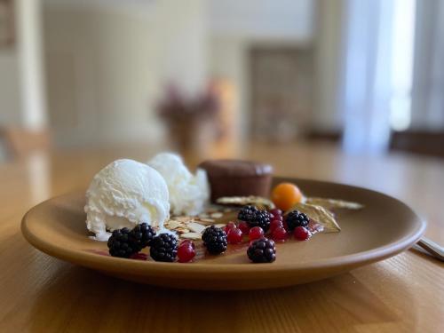 a plate with ice cream and berries on a table at Karle Hotel in Vitrupe