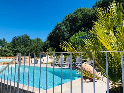 una valla alrededor de una piscina con sillas y árboles en Villa piscine privée vallée châteaux Dordogne en Saint-Cybranet