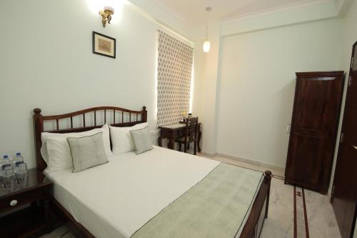 a bedroom with a bed with white sheets and a window at Jai Villa - A Boutique Hotel in Jaipur