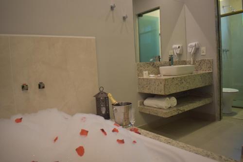 a bathroom with a tub and a sink and a mirror at Pousada Maria Monteiro Tiradentes in Tiradentes