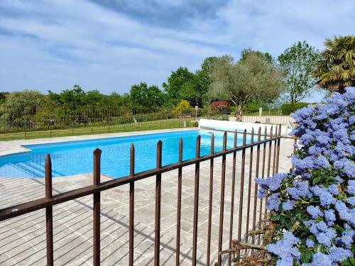 a fence with blue flowers next to a swimming pool at Les CASAS La Champrenière in Le Boupère