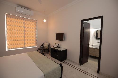 1 dormitorio con cama, ventana y espejo en Jai Villa - A Boutique Hotel, en Jaipur