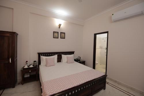 a bedroom with a bed with pink pillows and a mirror at Jai Villa - A Boutique Hotel in Jaipur