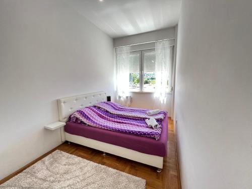 a small bedroom with a purple bed with a window at Jimmy's Apartment in Sarajevo