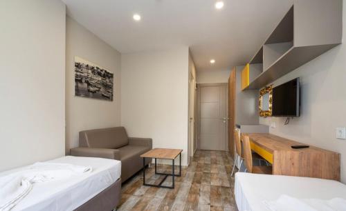 a room with two beds and a desk and a television at Dumlupınar Royal Rooms in Antalya