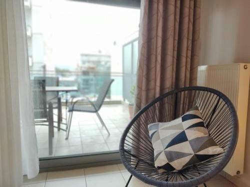 a chair with a pillow in a room with a balcony at Greg's Home Volos in Volos