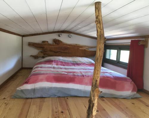 a bed in a tiny house with a wooden post at La pause tiny in Ploërmel