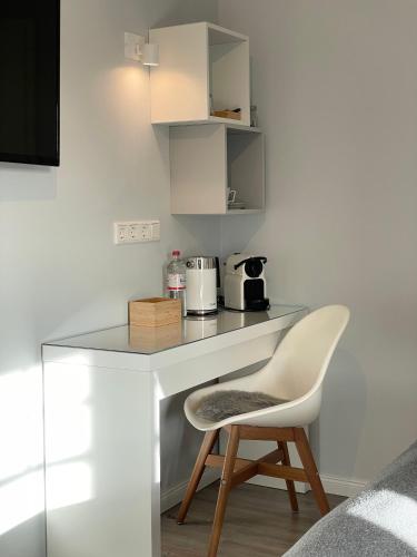 a white desk with a chair and a coffee maker at Landhaus Nordstern Hotel garni in Utersum