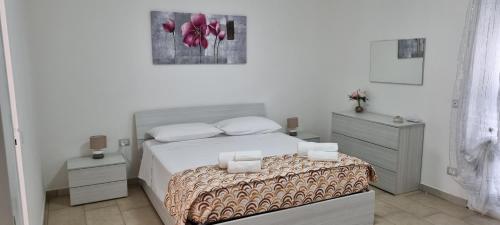 a white bedroom with a bed and two night stands at Appartamento Centro Niscemi in Niscemi