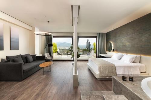 1 dormitorio con 1 cama y sala de estar con sofá en Heaven Hotel Thessaloniki Airport, en Néon Rýsion