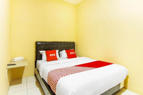 ein Schlafzimmer mit einem Bett mit roten Kissen darauf in der Unterkunft OYO 90900 Pagi Sore Residence in Padang
