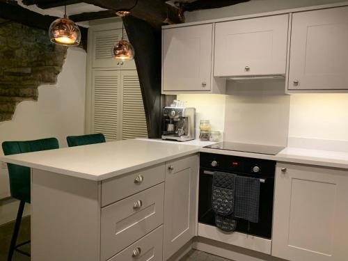 a kitchen with white cabinets and a stove top oven at Historic Grade II Listed Homely Cottage in Stamford