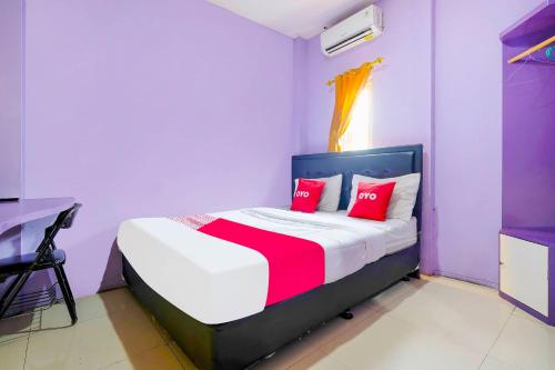 1 dormitorio con 1 cama con almohadas rojas en OYO 91299 Violet Guest House en Bandung