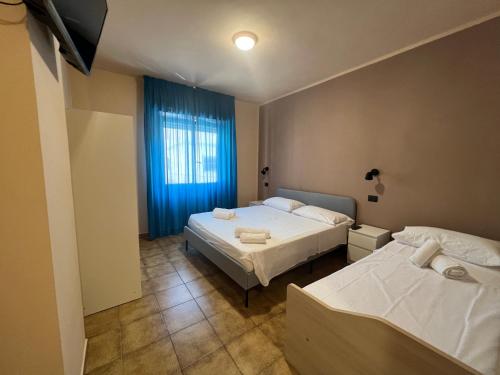 1 dormitorio con 2 camas y una ventana con cortinas azules en B&B Dal Pres, en Bagnara Calabra