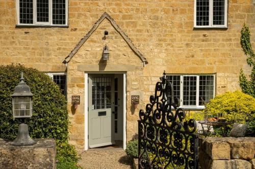 a brick house with a white door and a gate at Blenheim Cottage, Beautiful 15th Century Cotswold Cottage, 4 Bed, Nr Chipping Campden in Mickleton