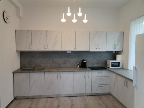 a kitchen with white cabinets and a sink and a microwave at Vila President Sovata in Sovata
