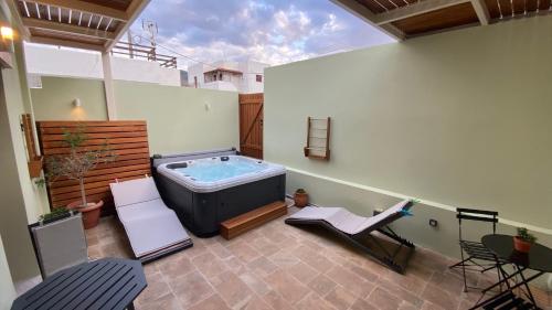 un patio con bañera de hidromasaje, mesa y sillas en Andros 4 All Seasons Villas & Suites, en Ándros