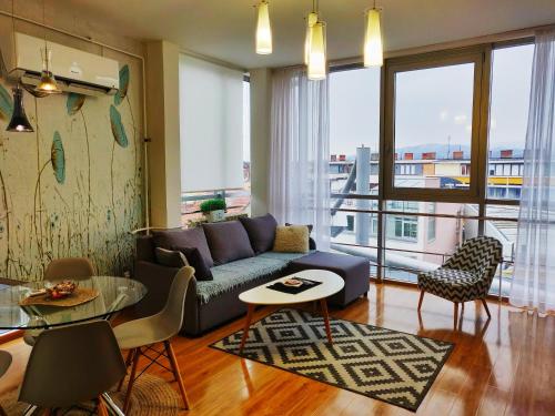 a living room with a couch and a large window at Apartman Lori M in Kraljevo