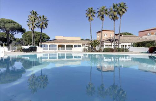 einem großen Pool mit Palmen und einem Gebäude in der Unterkunft Studio sur le Golf in Valescure