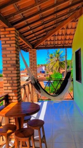 a porch with a hammock and a table and chairs at Chalé da Kikia in Icapuí