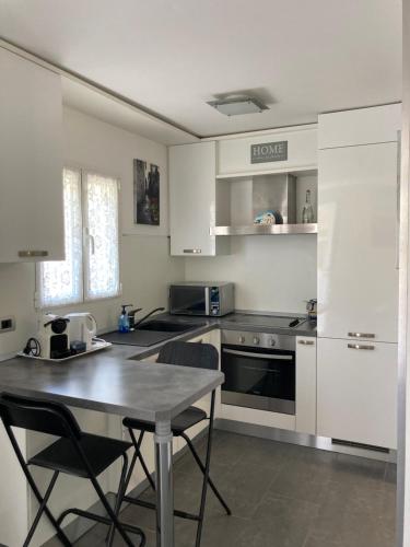 une cuisine avec des armoires blanches et une table avec des chaises dans l'établissement Studio Villa la Cigale avec grande Terrasse, à Menton