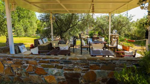 a patio with chairs and tables and a stone wall at Saint George Sithonia in Neos Marmaras