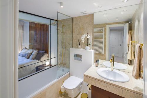 a bathroom with a sink and a toilet and a bed at Next to Puente Romano Newly done Modern style 5 star Luxury stay in Marbella